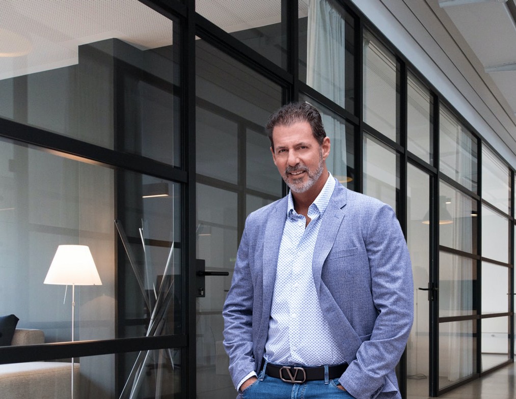 Rob Lancit in a light blue blazer standing beside glass office walls